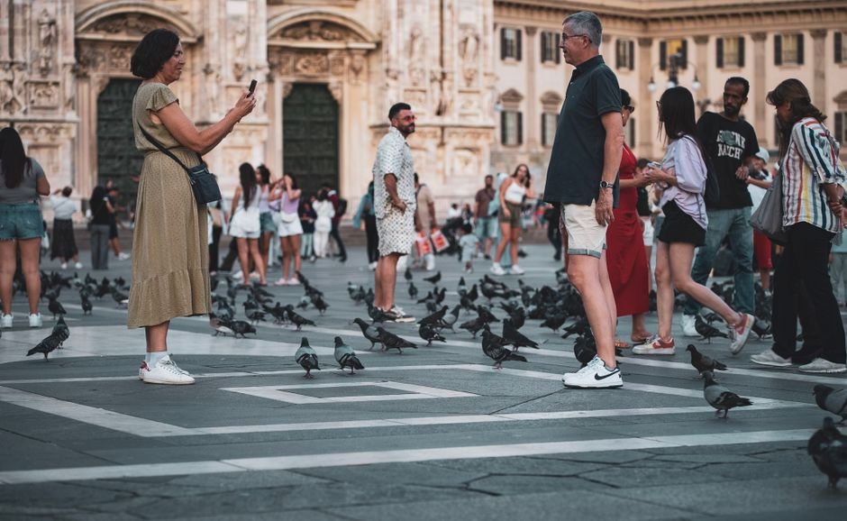 A lively scene at Milan's Piazza del Duomo with tourists and pigeons in front of the Duomo Cathedral.