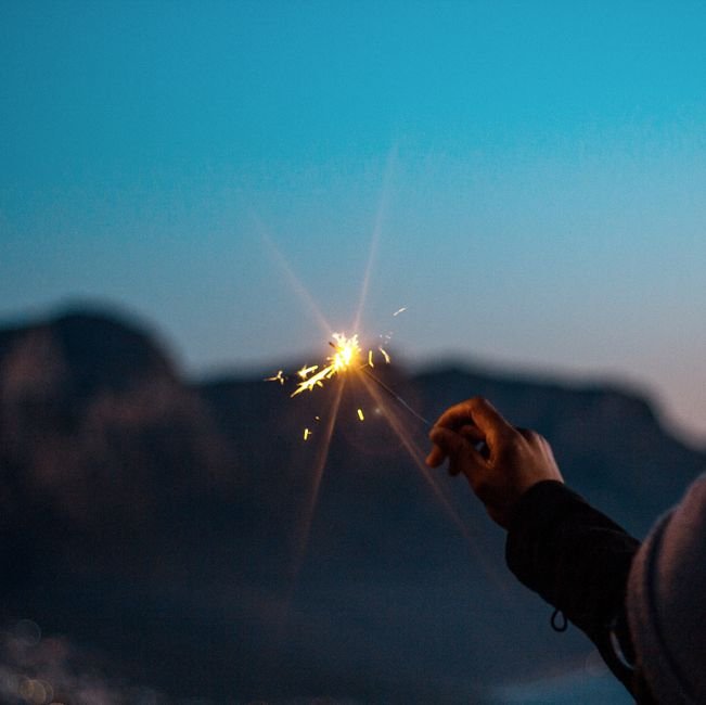 A hand holds a sparkler against a twilight sky in Cape Town, South Africa.