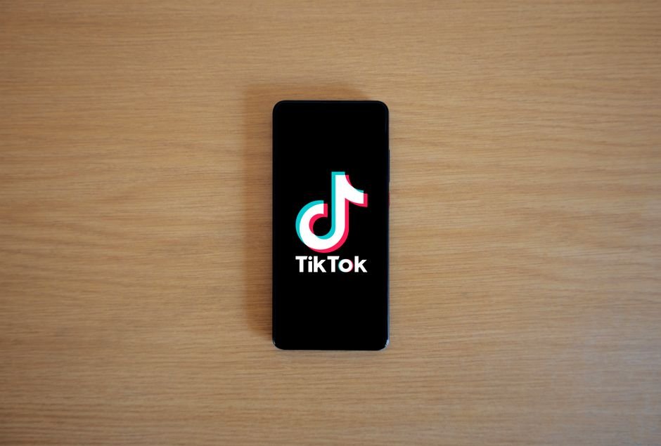 Smartphone with TikTok app displayed on black screen against a wooden background.